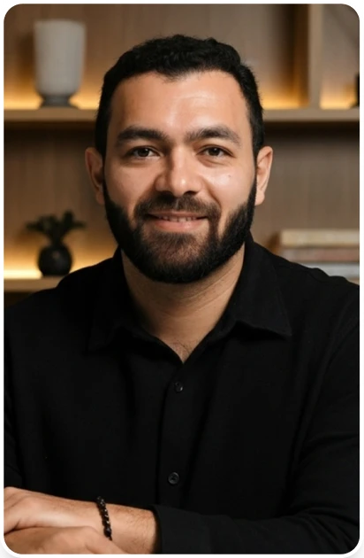 Dr. Leonardo Alano, médico em Fortaleza, sorrindo de camisa preta em seu consultório, com estante de madeira iluminada ao fundo