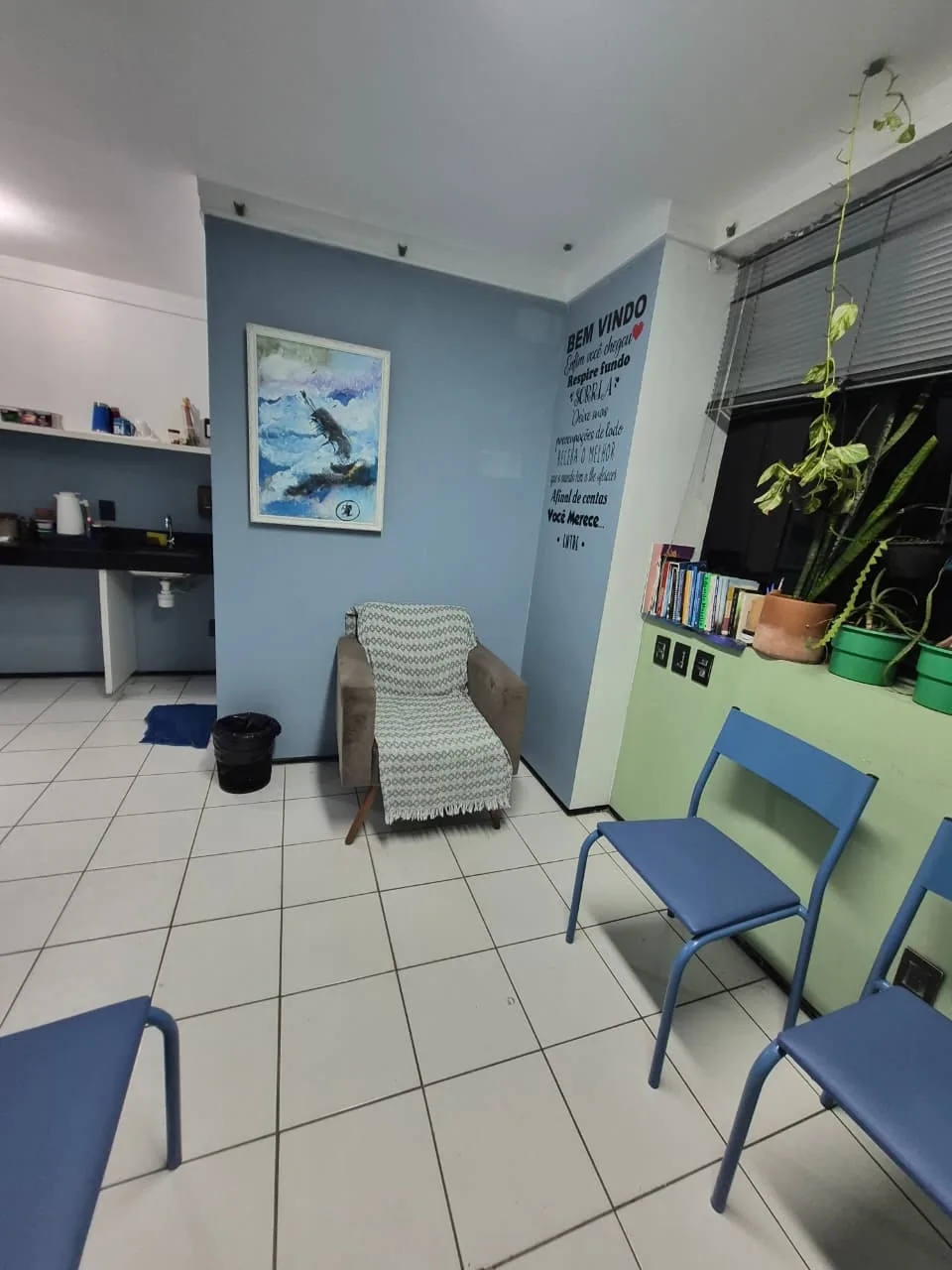 Recepção do consultório do Dr. Leonardo Alano em Fortaleza, com poltrona, cadeiras azuis e mural de boas-vindas