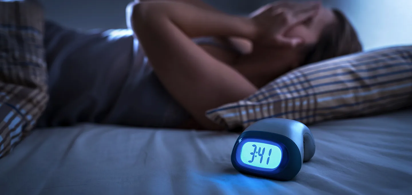 Homem acordado na cama durante a madrugada, sem conseguir dormir